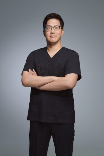 廖偉成醫師身穿診所制服交叉雙臂,展現自信與專業態度