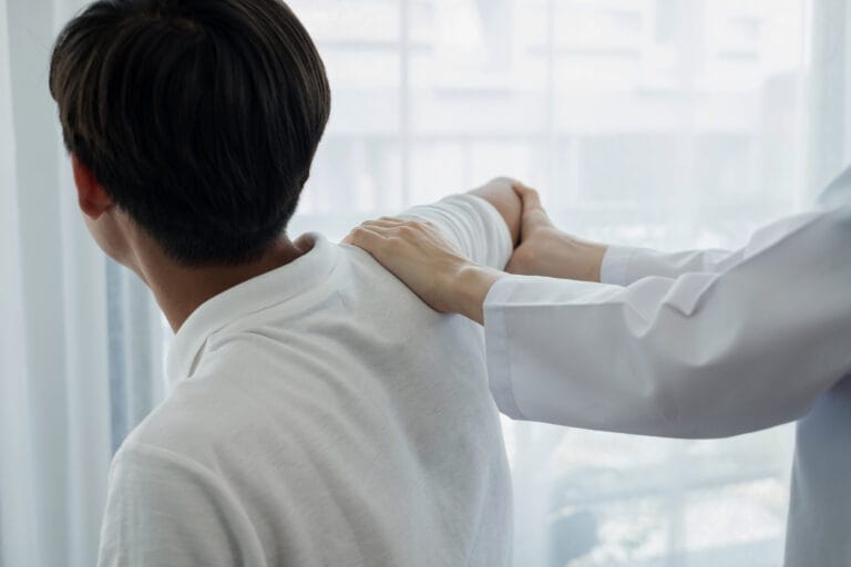 Female physiotherapists provide physical assistance to male patients with shoulder injuries massage their shoulders for muscle recovery in the rehabilitation center. Physiotherapy concepts.