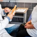 醫師手持膝關節模型,向坐在對面的患者說明關節構造