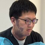 參加脊椎注射工作坊、穿黑色刷手服與藍色隔離衣的醫師,專注看向一側的半身照